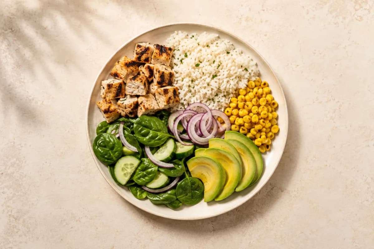 A plate of grilled chicken, rice, corn, spinach salad, cucumber and avocado being analyzed by CalorieCue