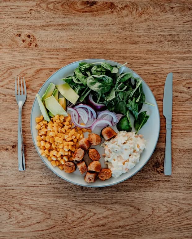A plate of grilled chicken, corn, spinach salad, avocado and red onion being analyzed by CalorieCue